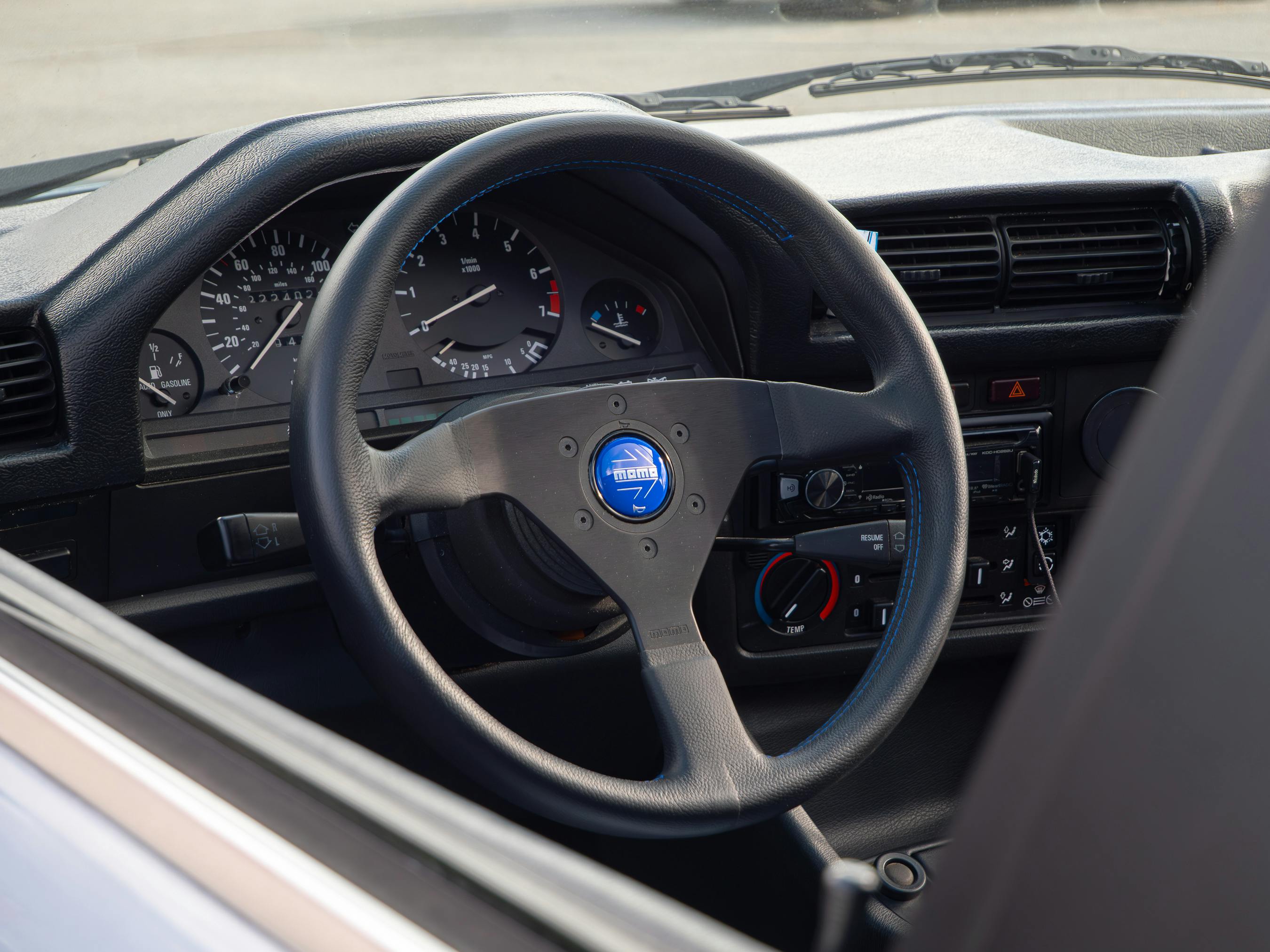 Close-up of a vintage car's steering wheel and dashboard showcasing classic design elements.