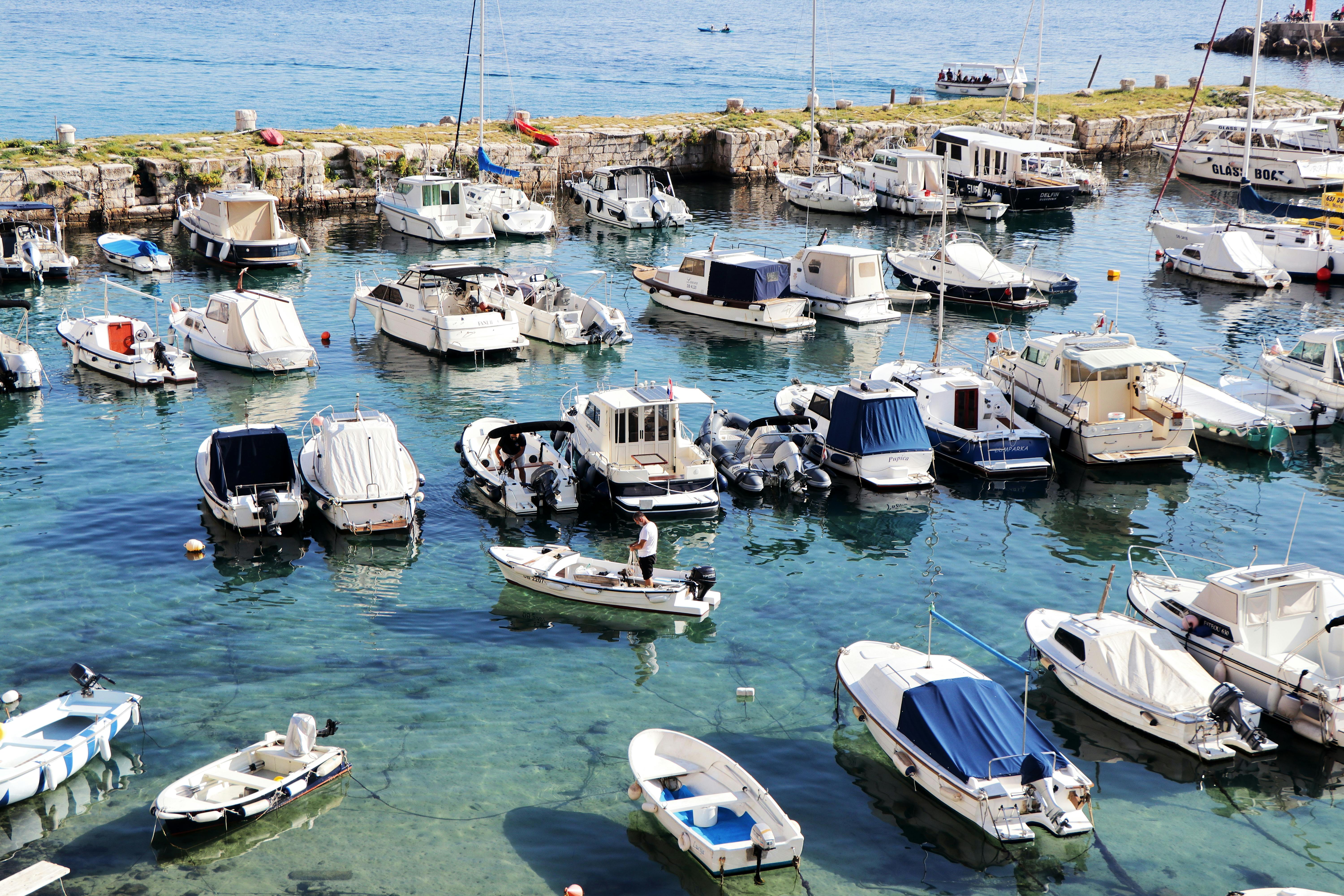 A picturesque view of boats docked at Dubrovnik harbor under a sunny sky, capturing the historical ambiance.