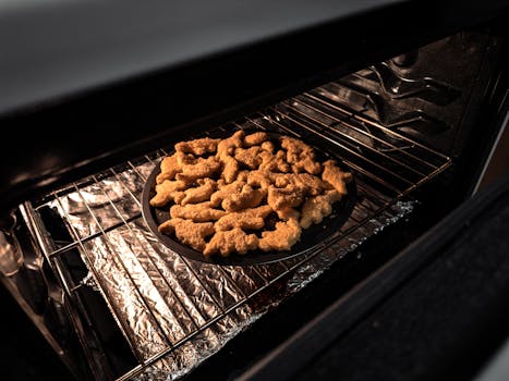 Close-up of animal-shaped chicken nuggets baking in an oven on a tray.