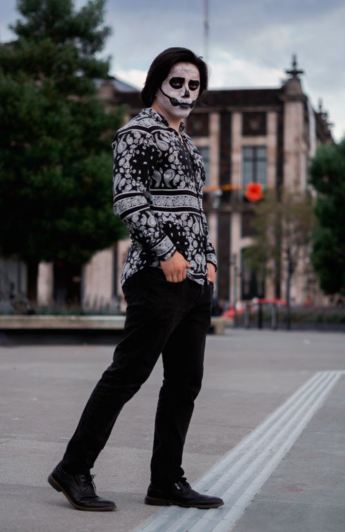 Free Man in Day of the Dead costume and makeup posing outdoors in urban setting. Stock Photo