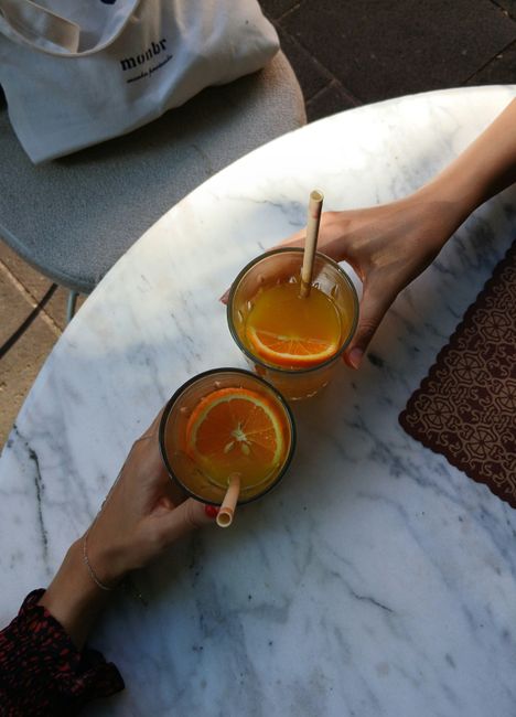Two glasses of fresh orange juice with straws on a marble table, creating a relaxing cafe vibe.
