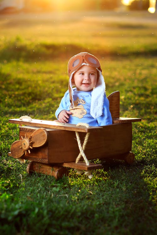 Photo of Baby Sitting on Wooden Airplane