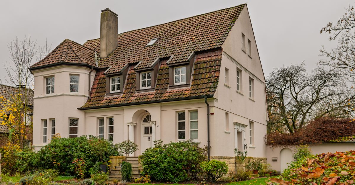 Elegant Tudor style house surrounded by autumn foliage, evoking a warm and cozy atmosphere.