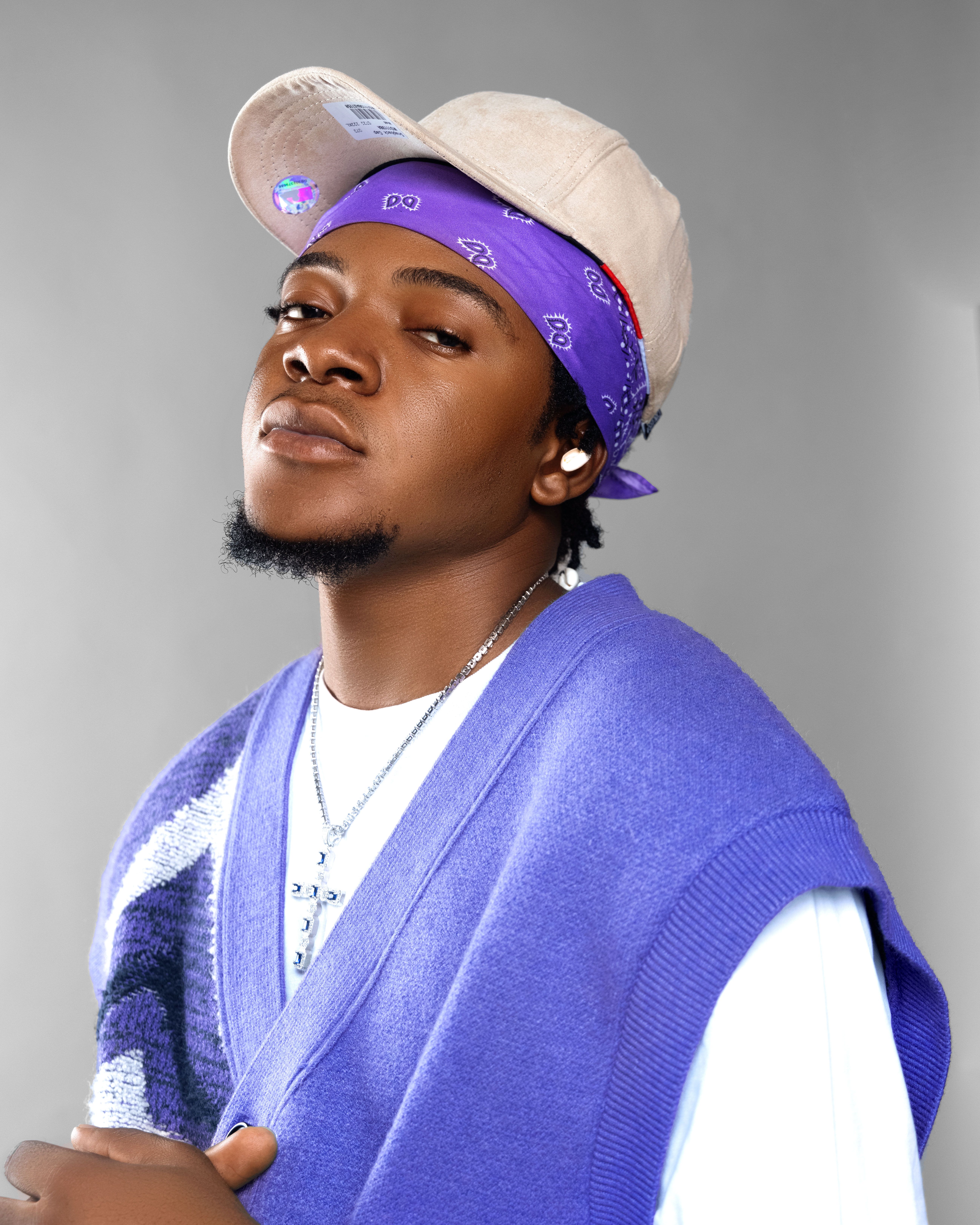 Portrait of a young man wearing a purple vest and bandana with a confident expression.
