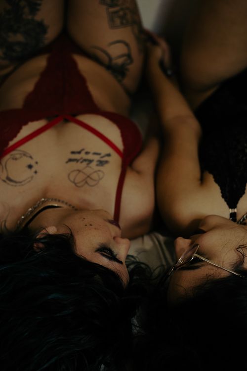 Free Close-up of two tattooed women lying together in intimate setting, expressing closeness and connection. Stock Photo