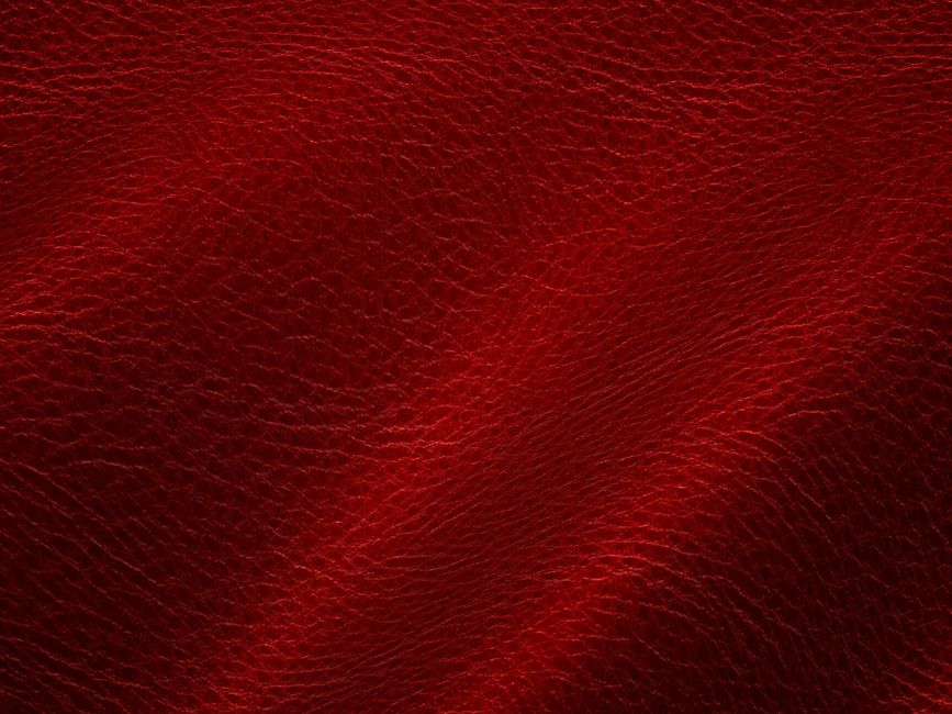 Close-up of a vibrant red leather texture featuring organic folds and natural patterns.