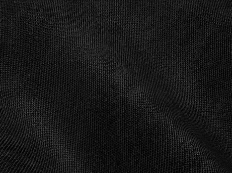 Close-up of a black textured fabric showing detailed weave and folds in high contrast.