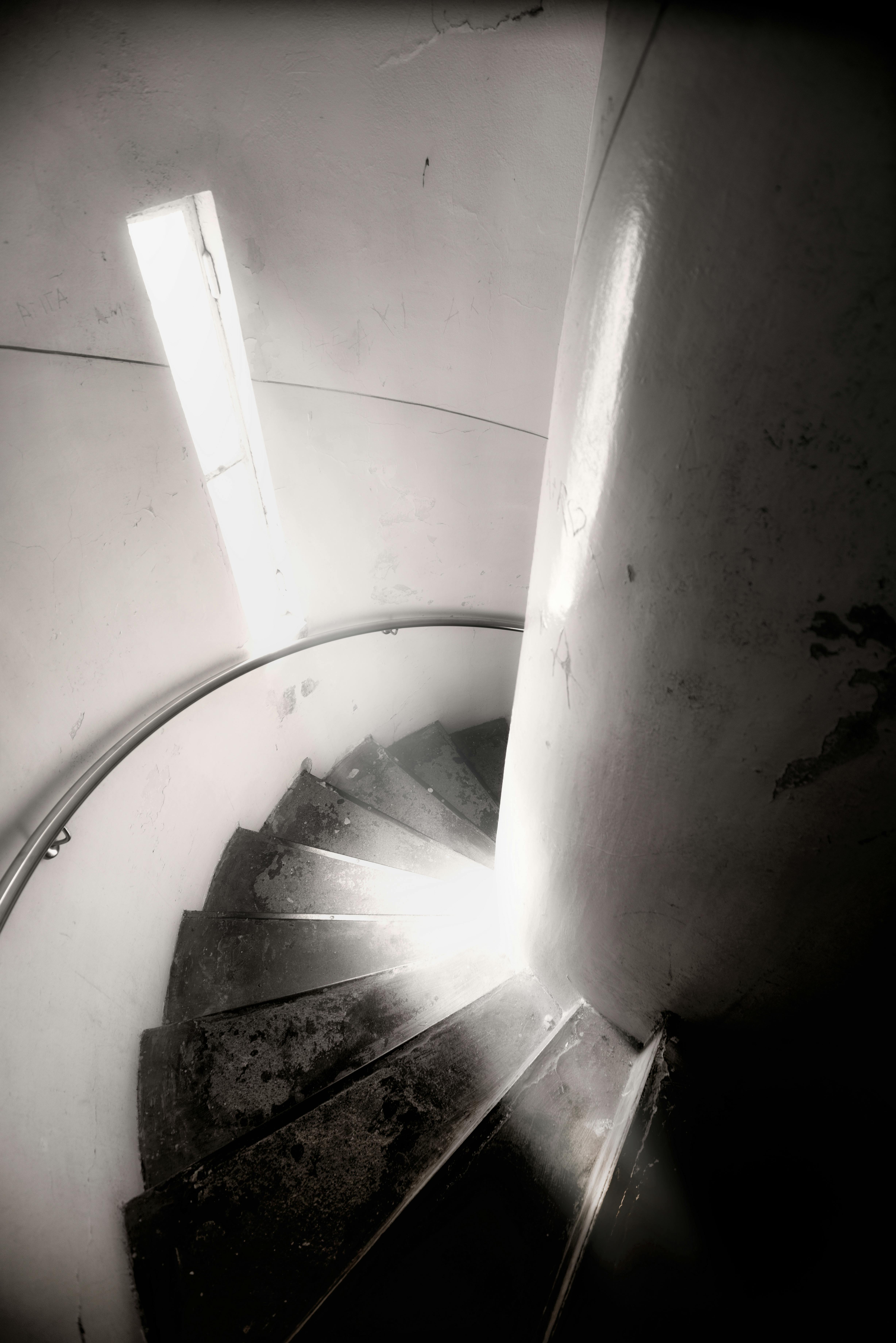 Black and white spiral staircase with dramatic lighting and shadows.