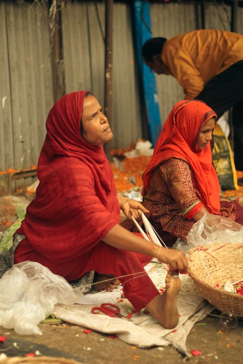 Free Women sorting flowers in Dhaka, Bangladesh, showcasing traditional clothing and market life. Stock Photo