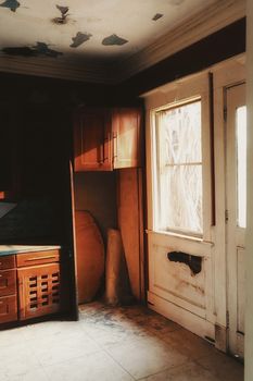 Sunlight streaming into an abandoned room with peeling paint and vintage furniture in Abuja.