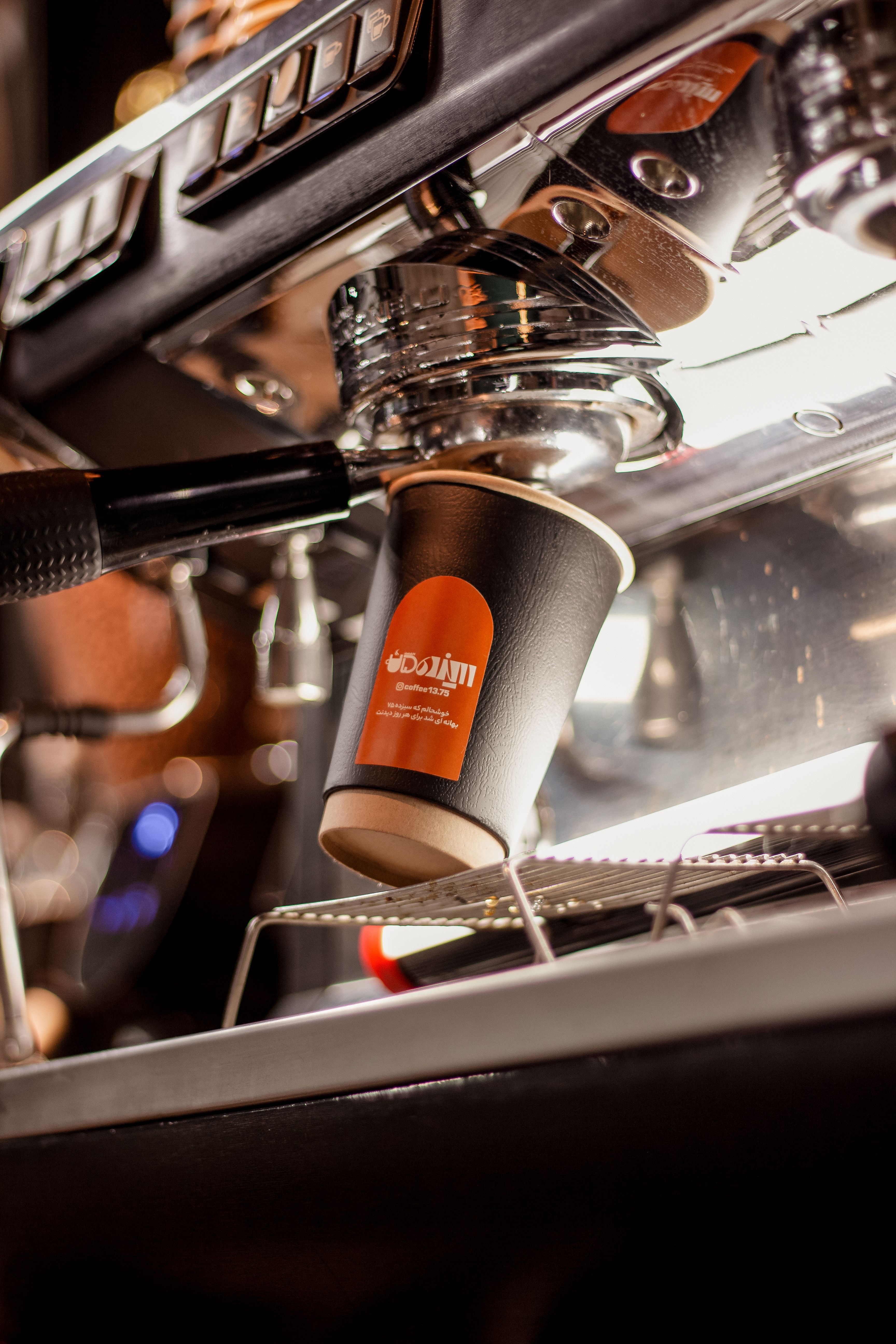 A detailed view of an espresso machine brewing coffee into a takeaway cup.