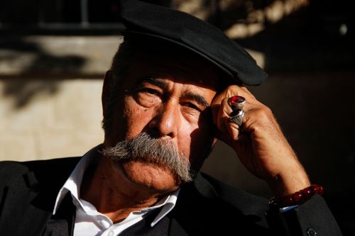 Free Close-up portrait of an elderly man wearing a cap, deep in thought, in warm sunlight. Stock Photo