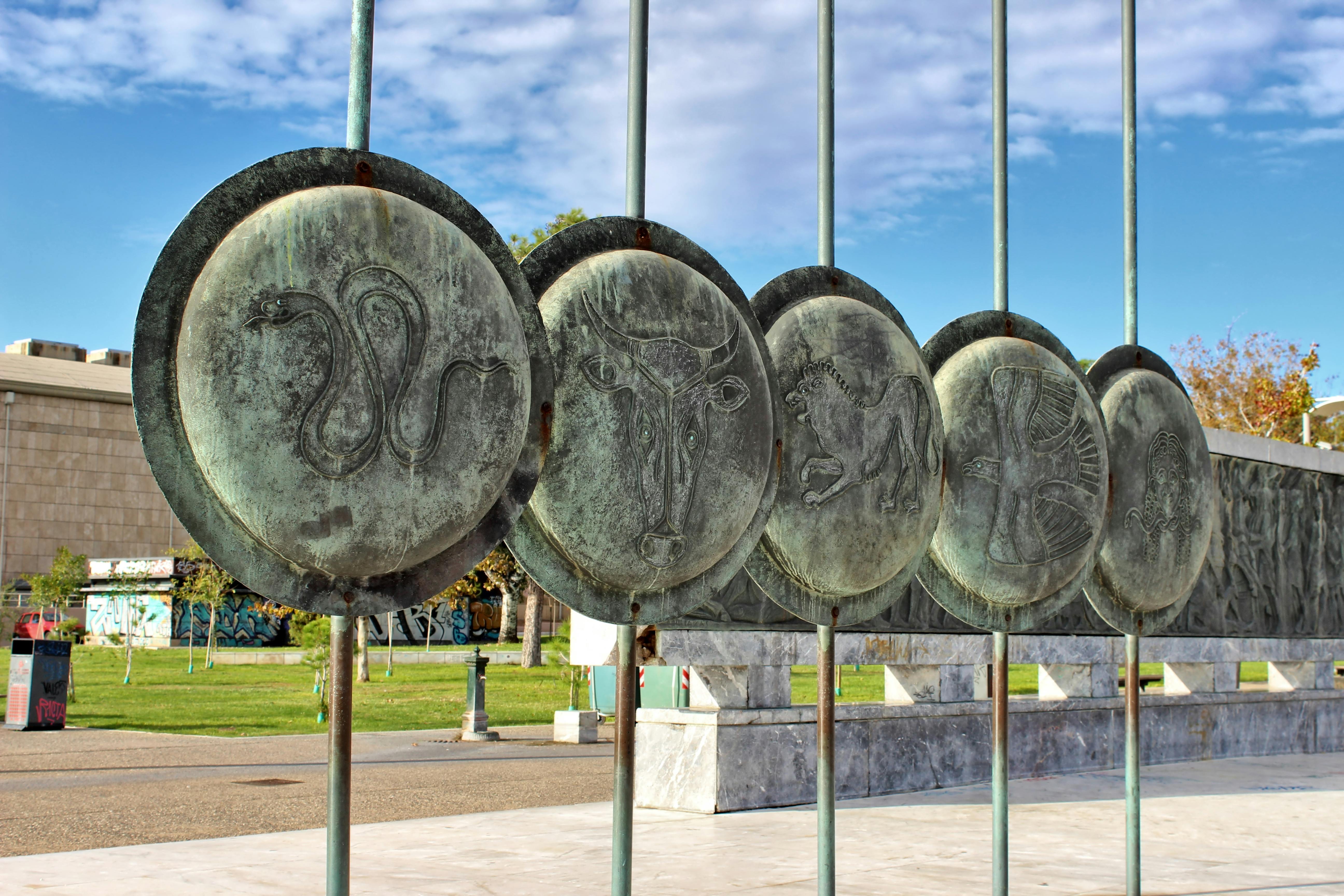 Bronze zodiac symbols displayed as art in a Thessaloniki park.