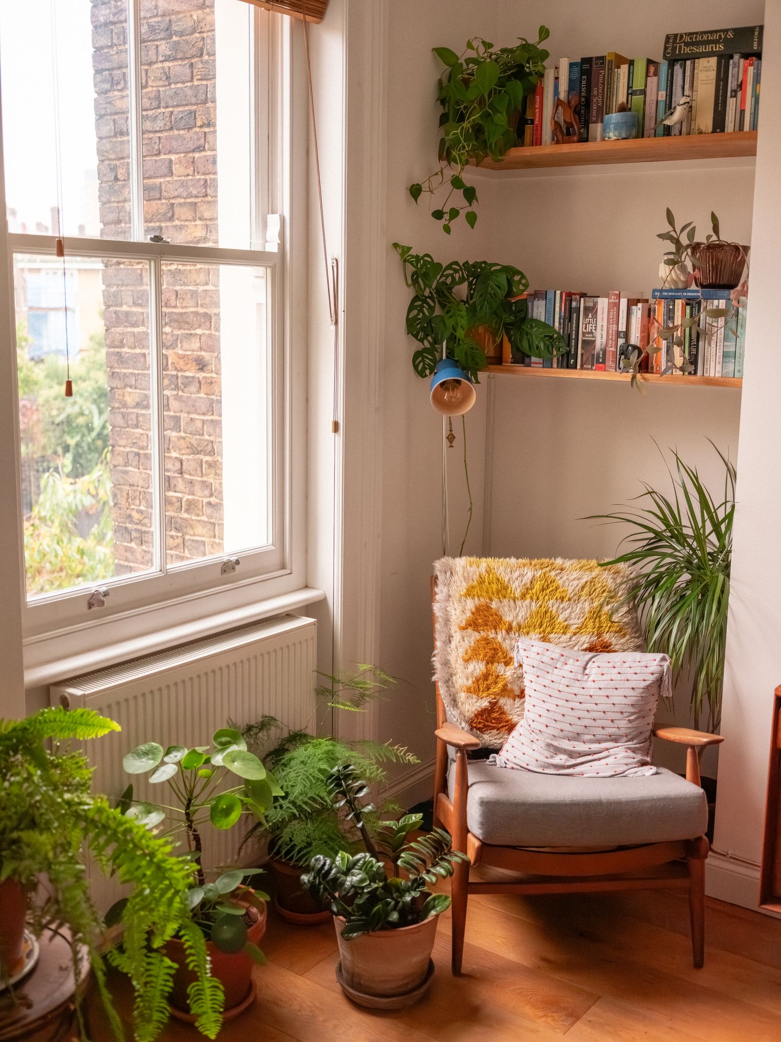 Sunlit plant-filled calm reset corner with books and a comfortable chair