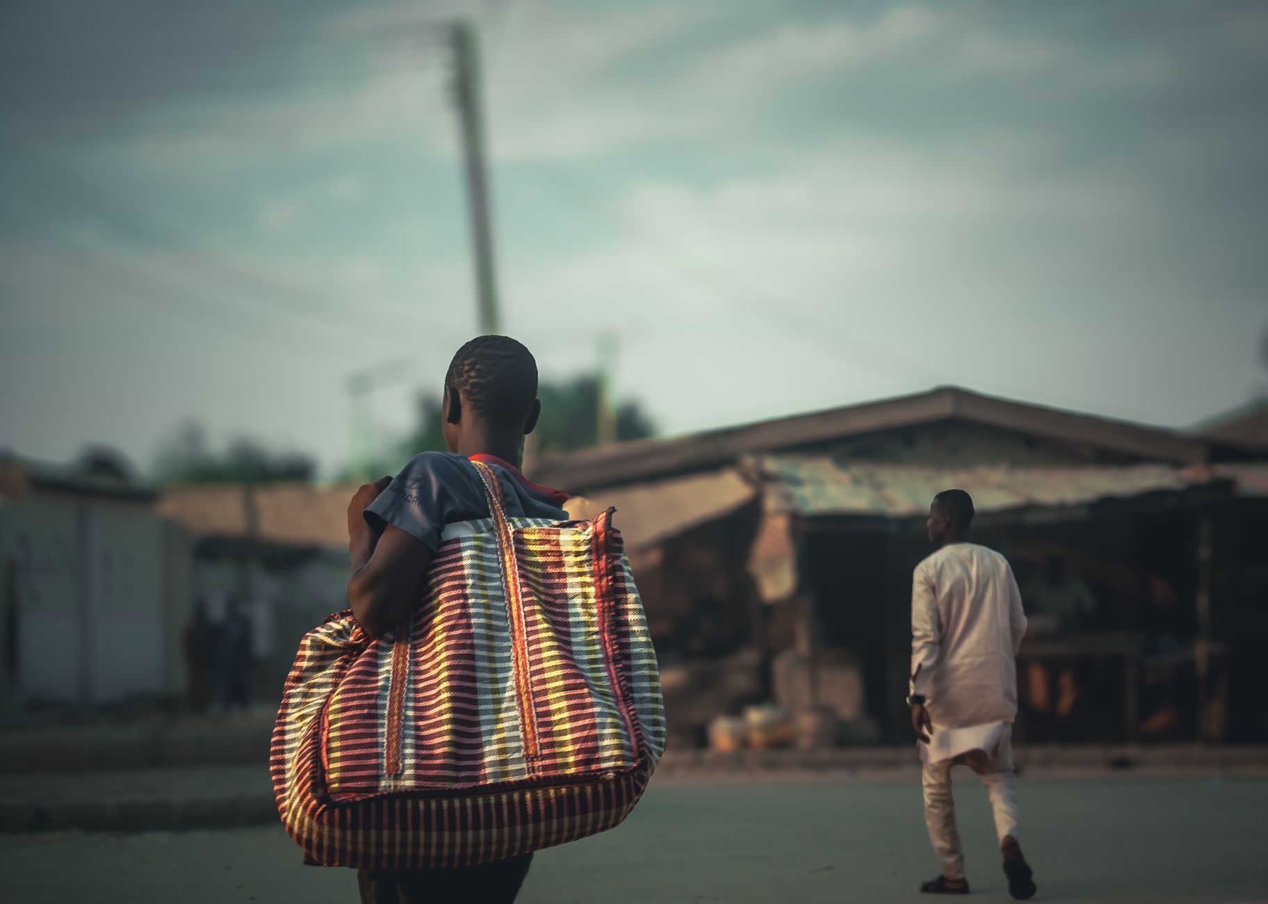 A vibrant street scene in an African town featuring a person carrying a colorful striped bag.