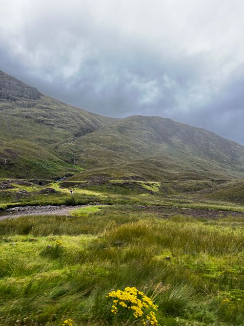 Free Picturesque view of lush Scottish Highlands with rolling hills under a cloudy summer sky. Stock Photo