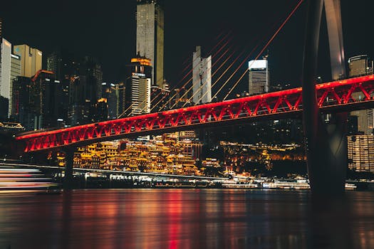 Stunning night view of Chongqing with illuminated bridge and city lights reflecting on water.