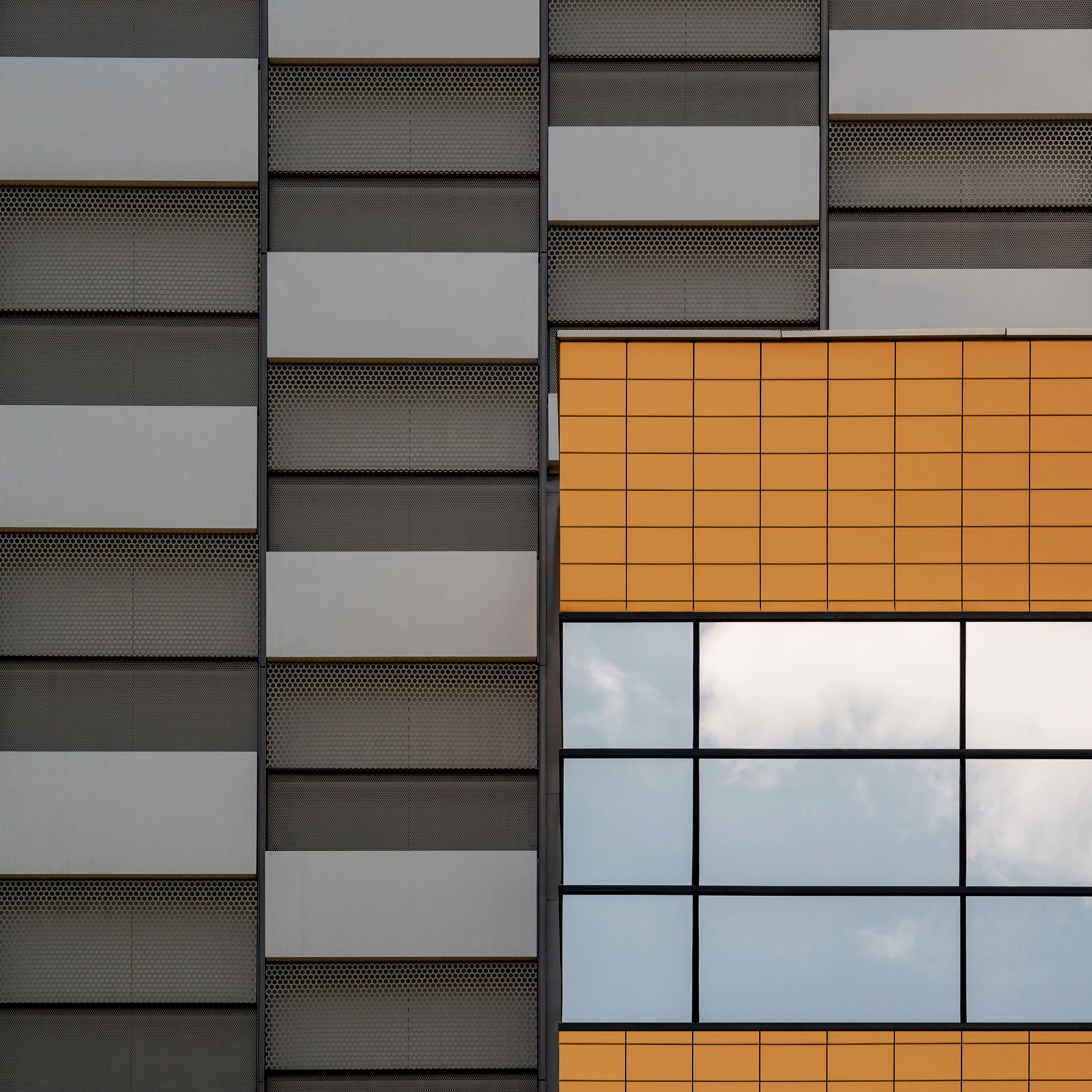 Abstract view of a modern building facade with orange and gray panels showcasing minimalism.