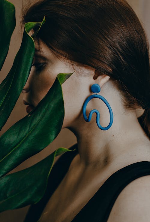 女人穿著綠色的樹葉附近的藍色耳環的照片