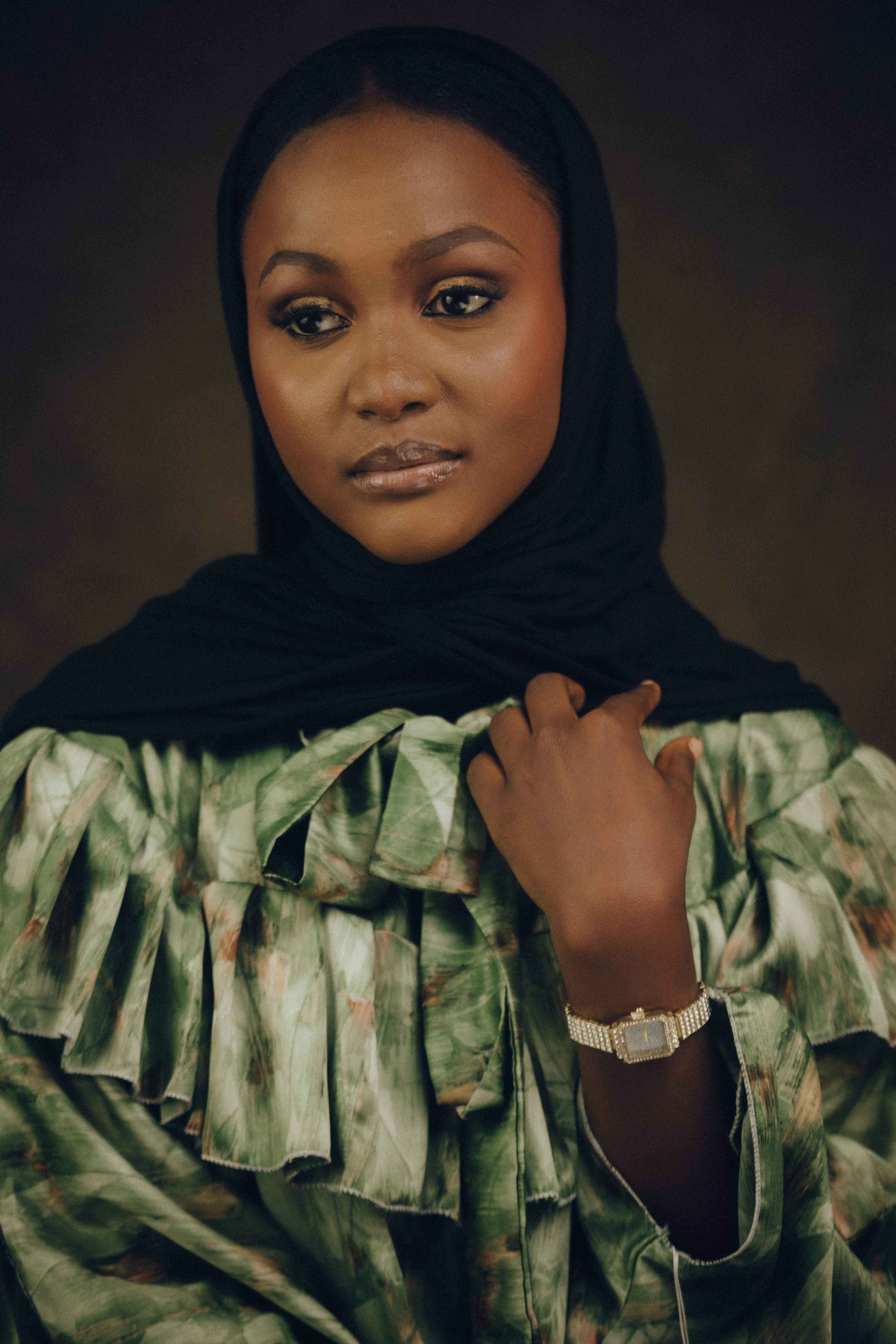 Stylish portrait of a woman with a black hijab and patterned dress, exuding elegance.