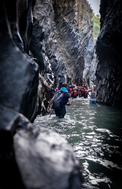 Free Group of people hiking through a narrow rocky gorge with water. Stock Photo