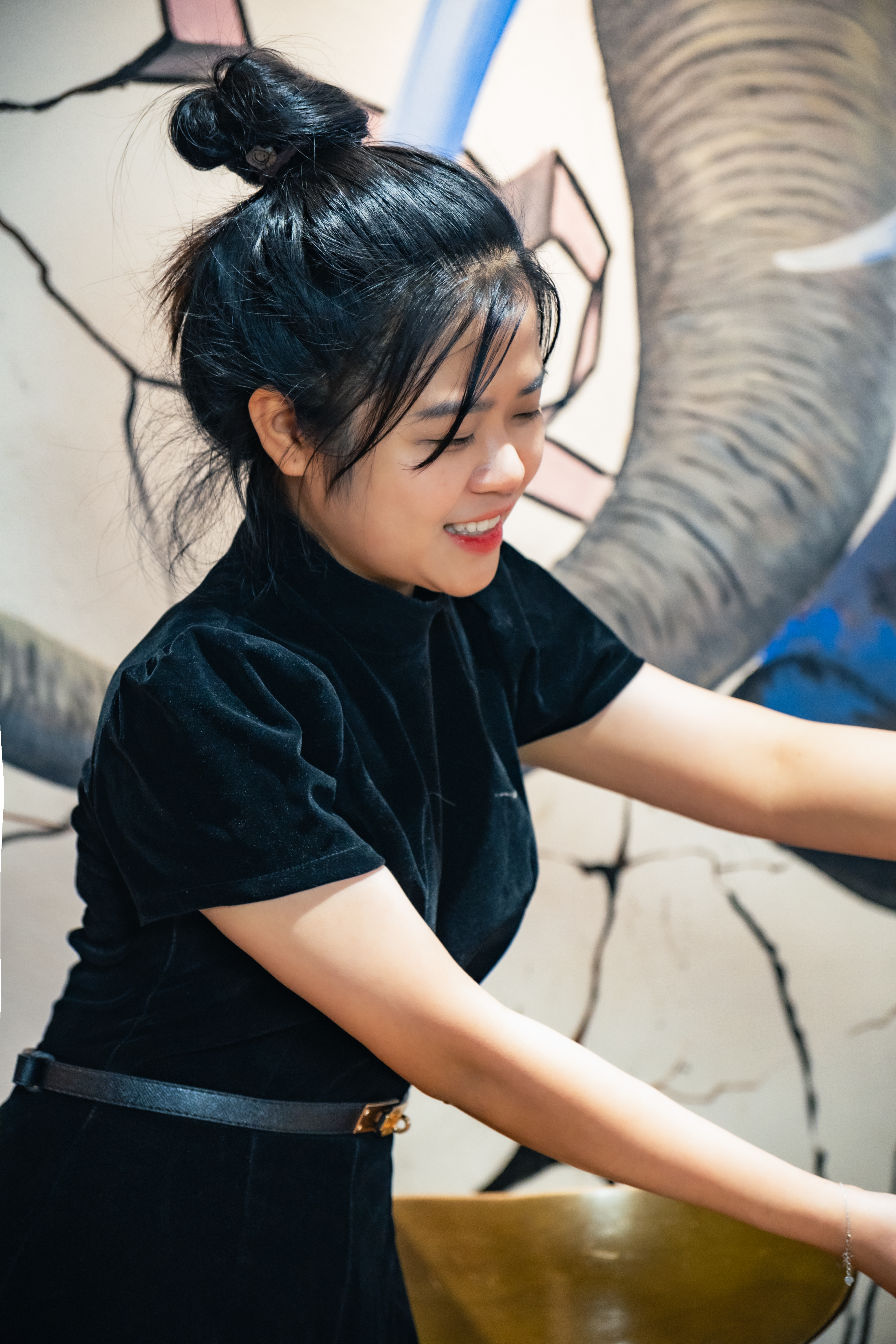 Smiling young woman in an Vietnamese café with artistic mural background.