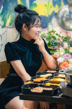 A young woman enjoys a warm meal in a cozy Vietnamese restaurant with vibrant decor and flowers.