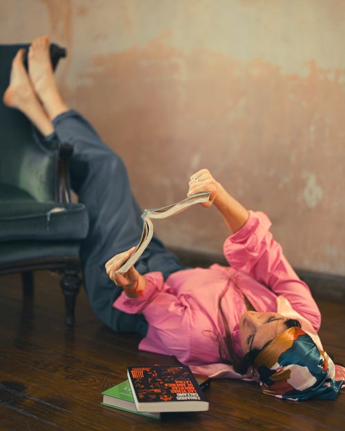 Free Woman in casual attire reading a magazine on the floor beside an armchair. Stock Photo