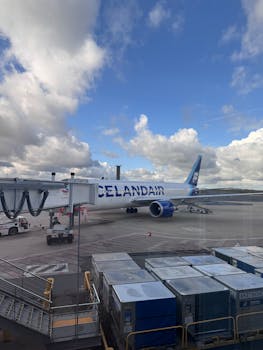 Icelandair airplane parked at airport gate under a cloudy blue sky.