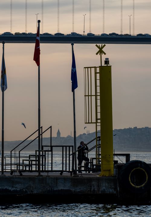 Free Silhouette of a man on a dock with Bosphorus Bridge and Maiden's Tower in the background during twilight. Stock Photo