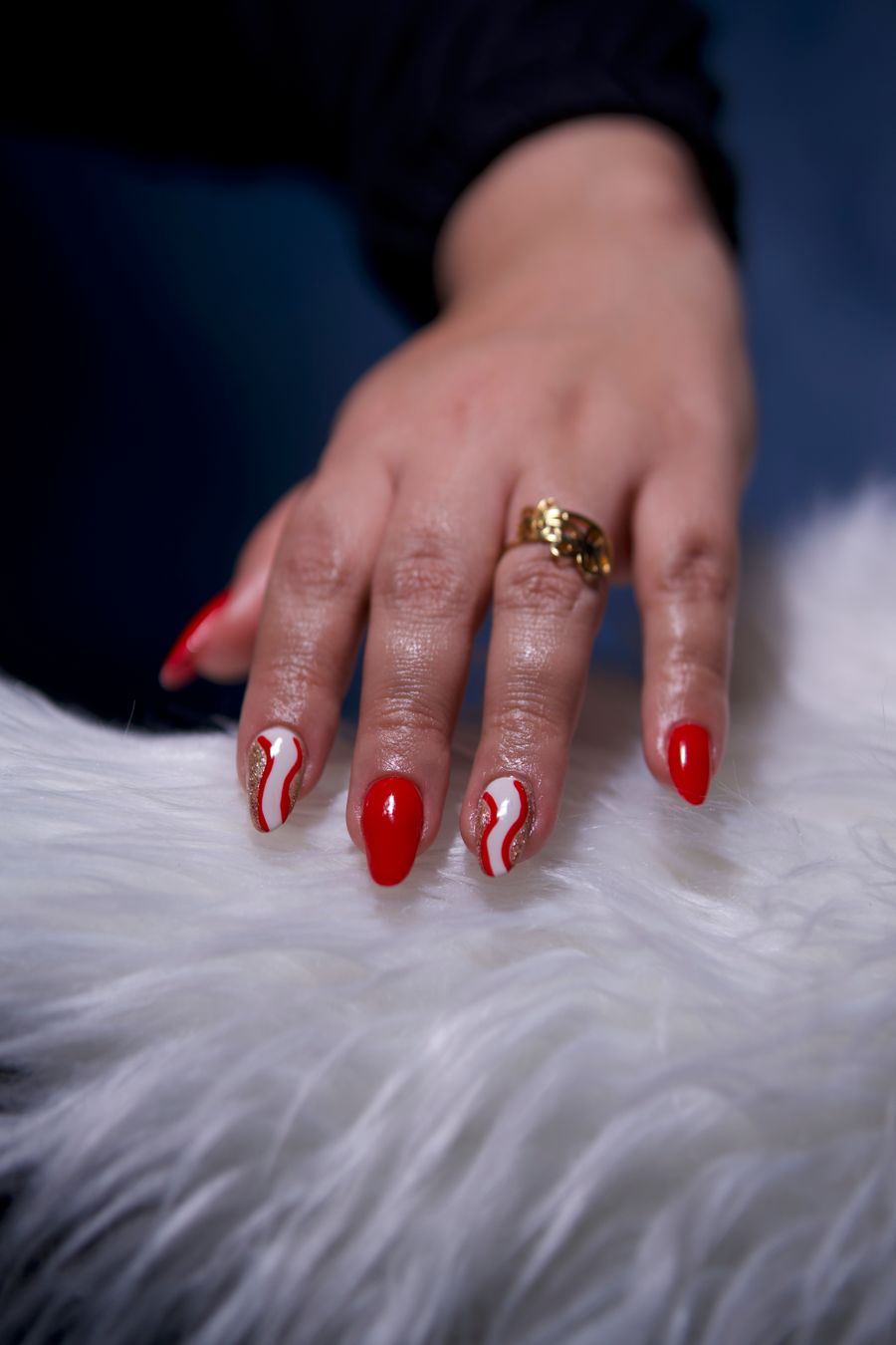 Red manicure with white-and-gold accent on white fur — Hush nail studio