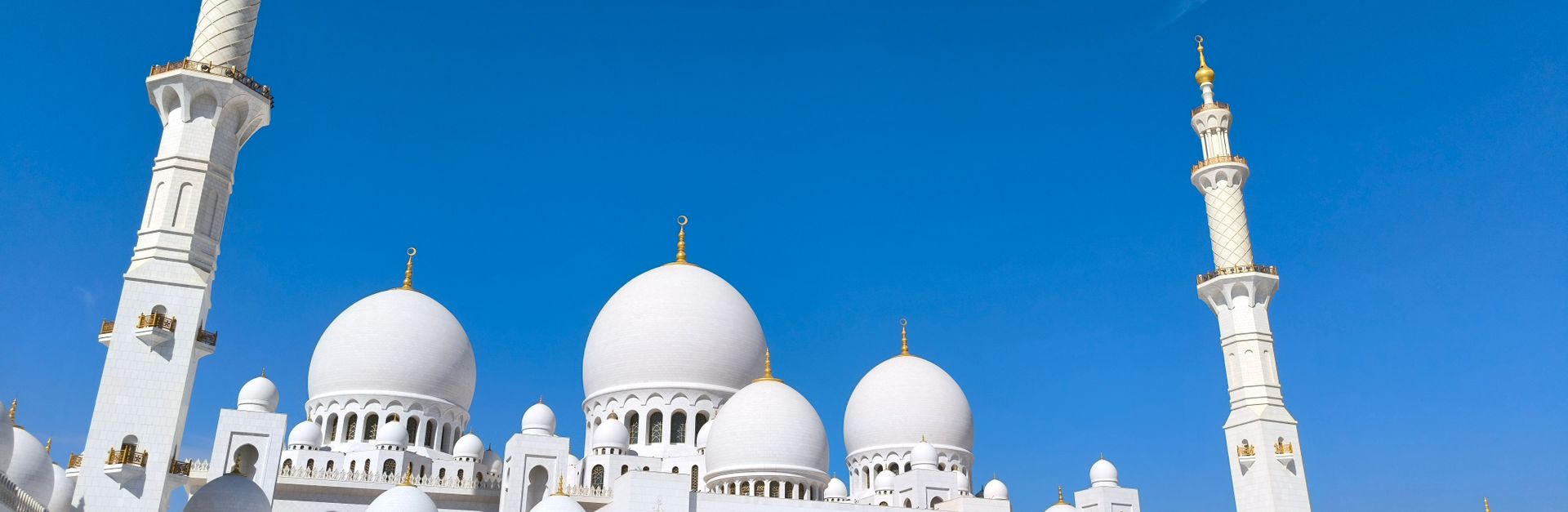 A stunning architectural capture of Sheikh Zayed Grand Mosque under a clear blue sky in Abu Dhabi.