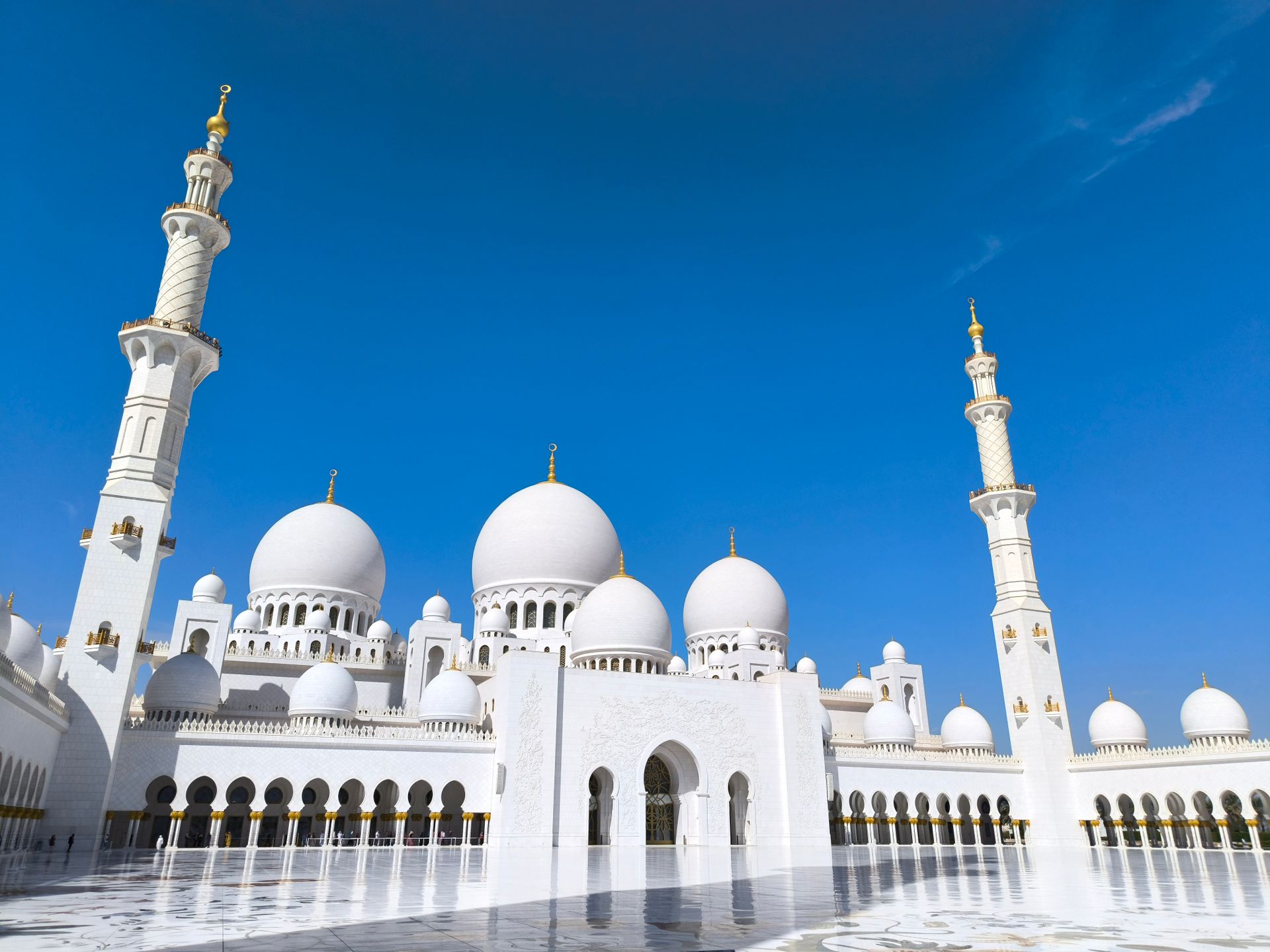 A stunning architectural capture of Sheikh Zayed Grand Mosque under a clear blue sky in Abu Dhabi.