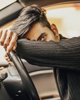 时尚男模特在车内摆出造型，显得深思熟虑且前卫