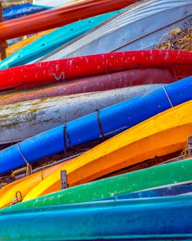 Vibrant lineup of kayaks arranged side by side outdoors, showcasing their colorful designs.