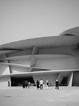 Monochrome view of the National Museum of Qatar's dynamic architecture with visitors.