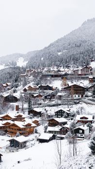 A picturesque view of a snow-covered alpine village with traditional wooden houses.