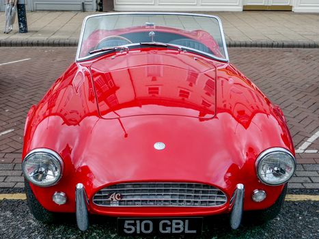 Capture of a vintage red AC sports car parked on a street in Northallerton, UK.