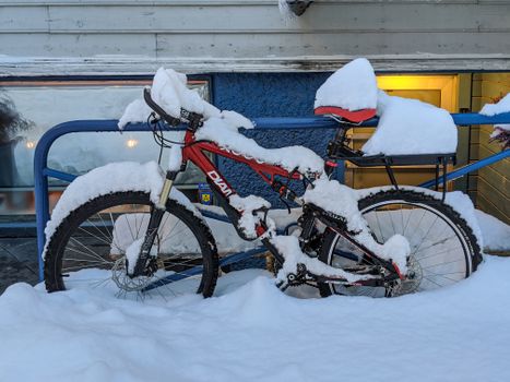Red bicycle buried in snow outside a building in Åndalsnes, Norway.