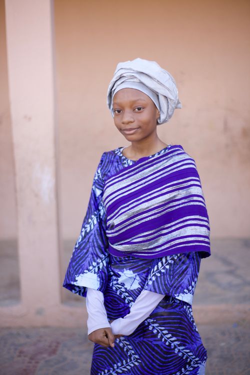 Free Portrait of a young girl in vibrant traditional African clothing with a soft smile. Stock Photo