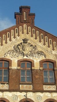 Close-up of a decorative facade on a historic brick building under blue sky.