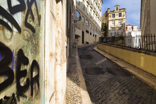 Free A scenic view of a narrow cobblestone street in Lisbon with traditional architecture and colorful buildings. Stock Photo