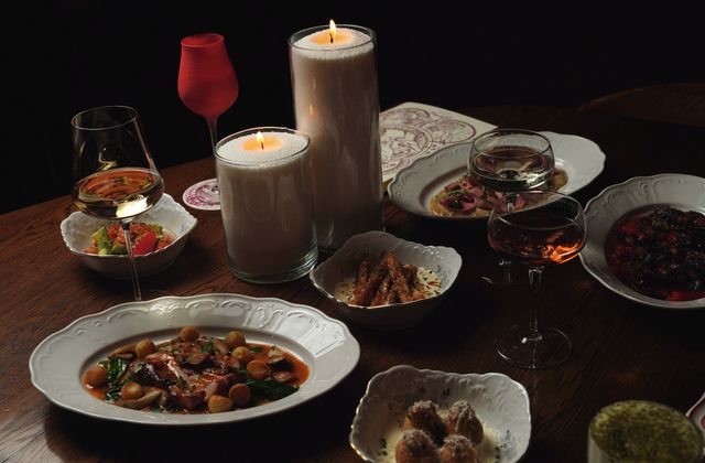 A dinner table laid with candlelight and plated food