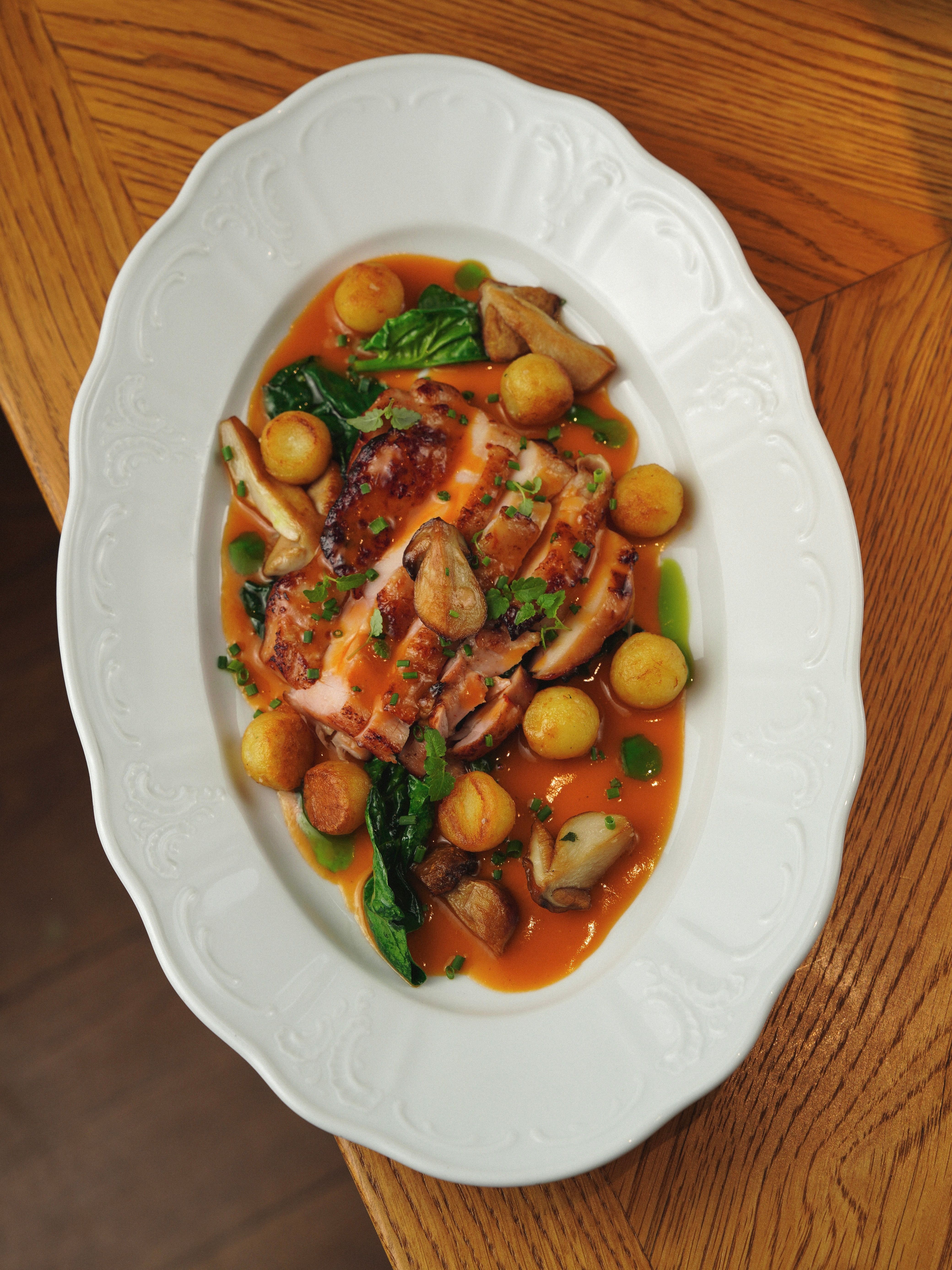 Delicious grilled chicken with vegetables and gravy on a white plate.