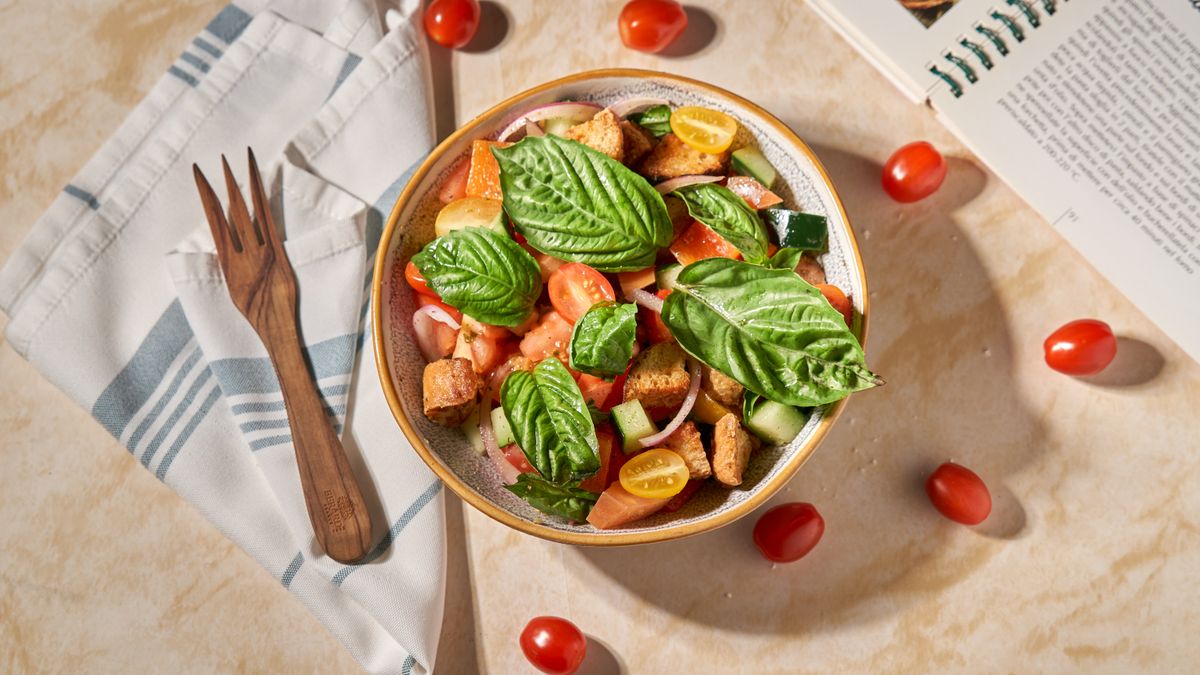 Panzanella with toasted bread cubes, red and yellow tomatoes, cucumber and large basil leaves