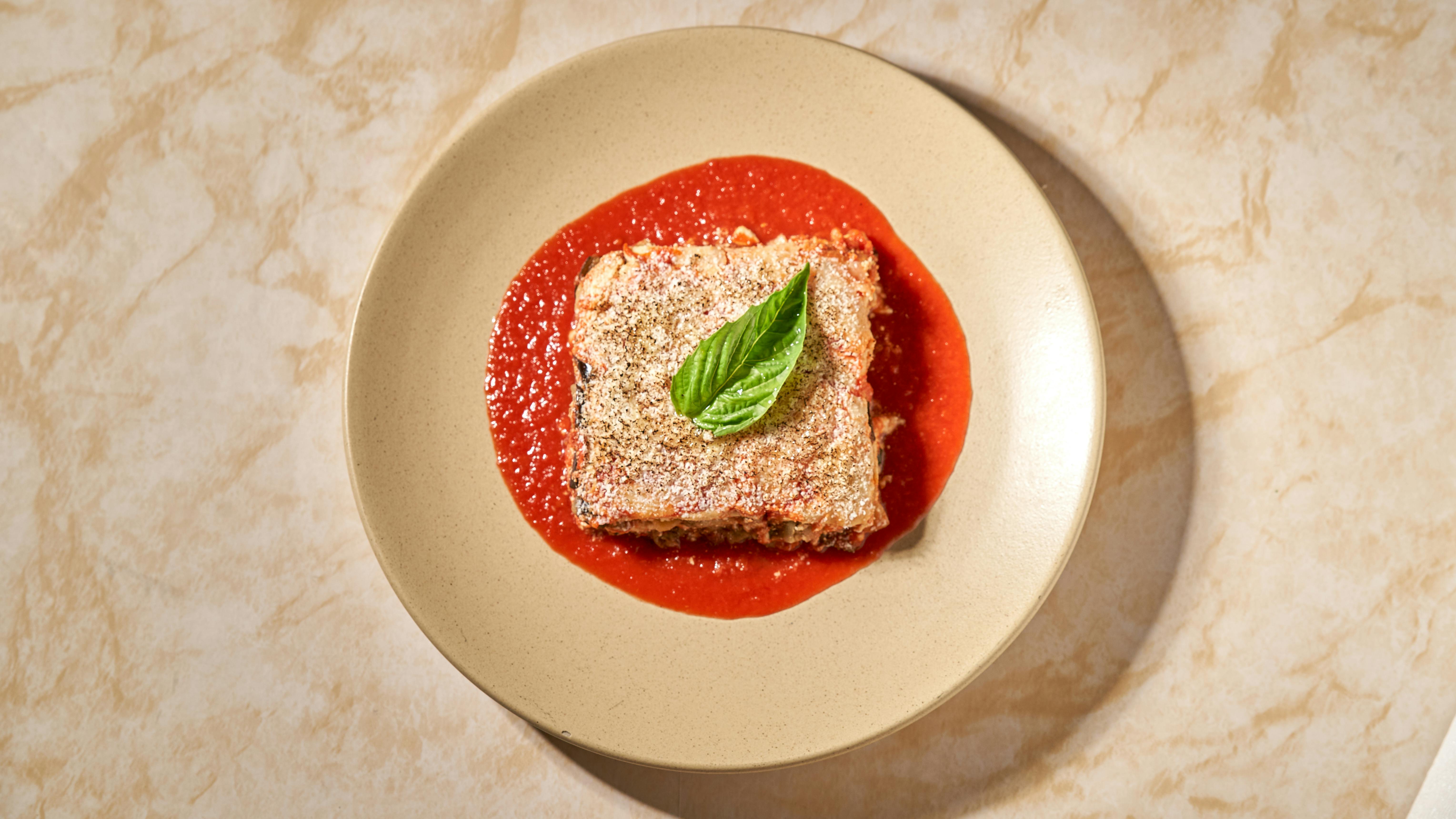 Un savoureux plat d'aubergines à la parmigiana, servi avec une sauce tomate et du basilic.