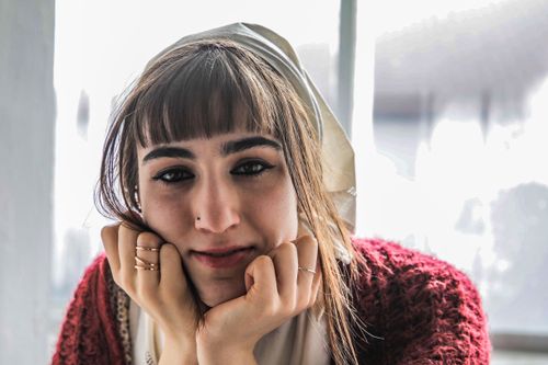 Free A woman with a thoughtful expression gazes warmly into the camera indoors. Stock Photo