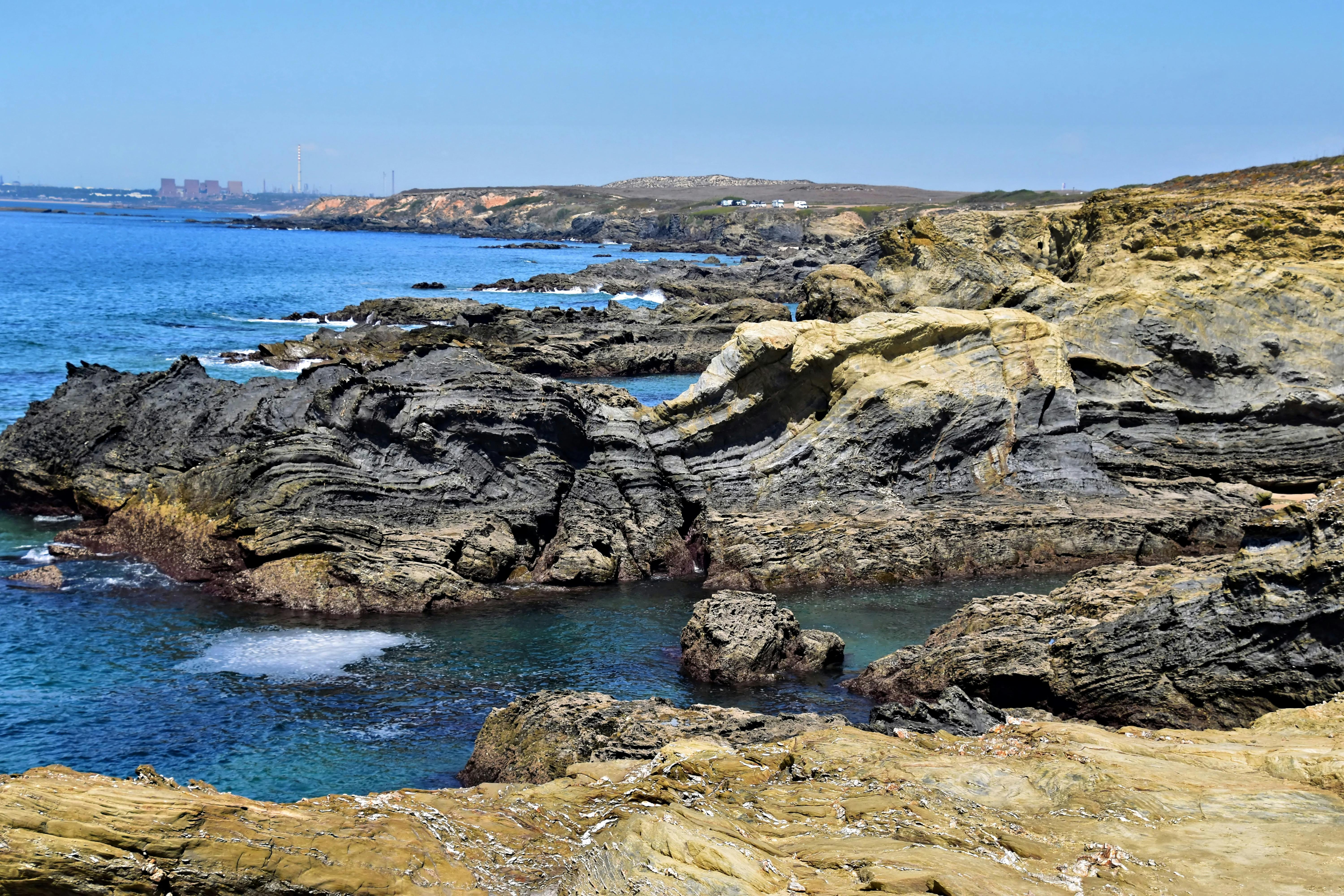 Explore the rugged beauty of Setubal's stunning coastal rock formations against a clear blue ocean.