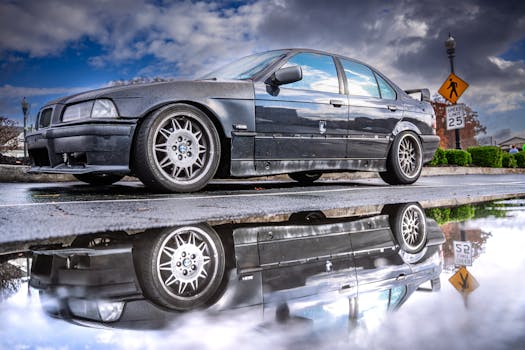 A vintage BMW car beautifully reflected in a puddle with dramatic clouds overhead.