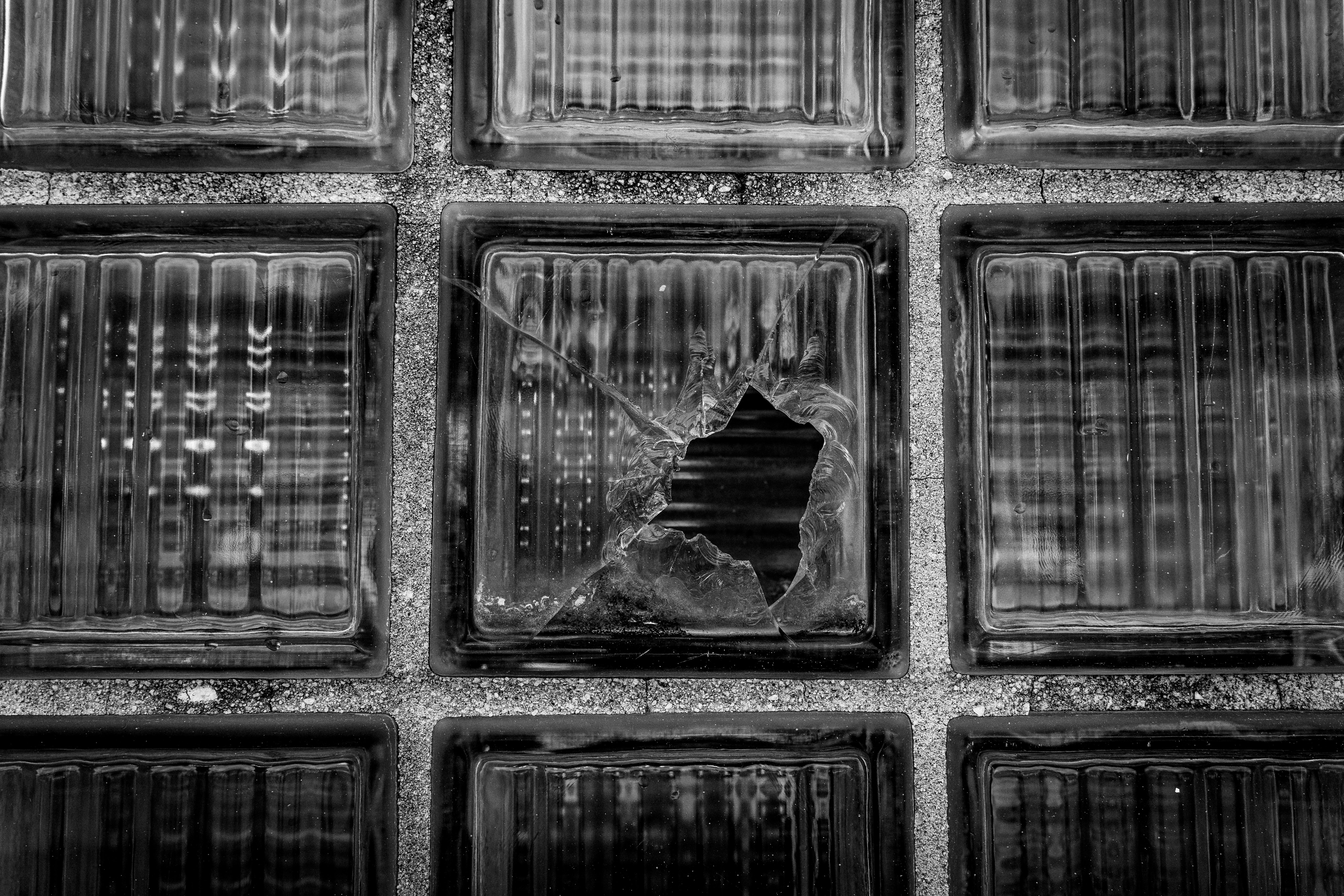 A black and white photo of a cracked glass block in an industrial setting, offering artistic texture.